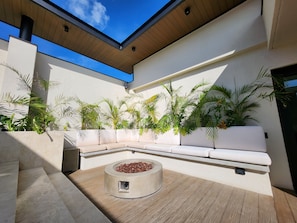Uma área de estar moderna ao ar livre, com um banco embutido e lareira.