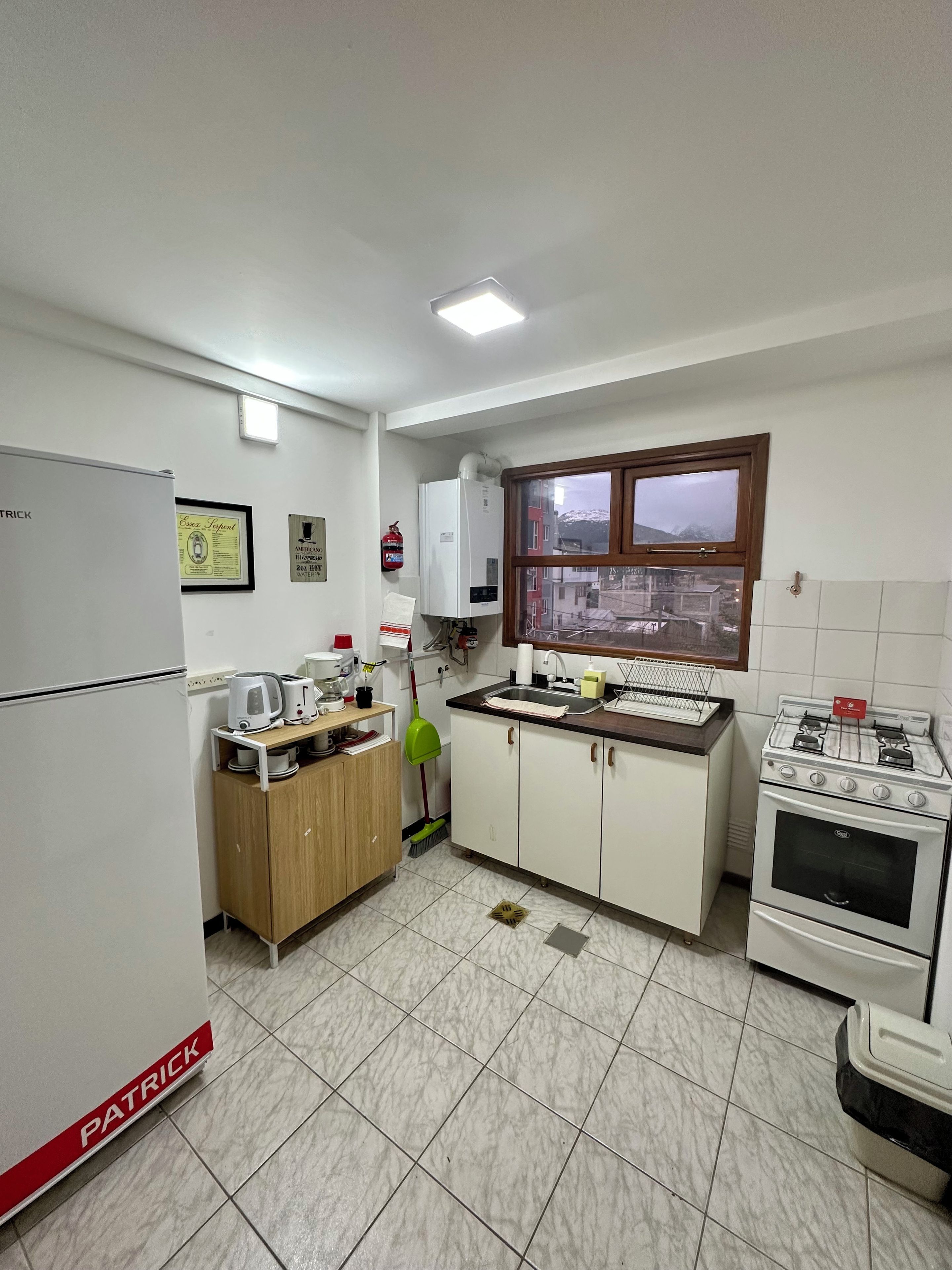 Una cocina con refrigerador, estufa, lavaplatos y ventana con vistas.