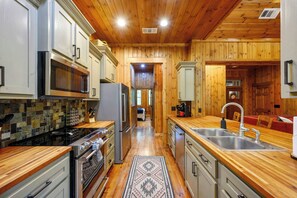 A modern kitchen with wooden cabinets, stainless steel appliances, and a central island with a sink. - Classic! Away From It All! Hot Tub-Firepit-Arcade! (Broken Bow)