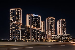 A high-rise building complex with illuminated signage, multiple floors, and a modern architectural design. - Stylish 1BR Dubai.Balcony & Skyline View (Dubai)