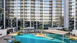Un edificio alto con piscina en la azotea y tumbonas.