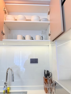 Une cuisine équipée d’un évier, d’un robinet et d’un porte-ustensiles.