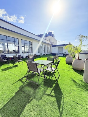 An outdoor seating area with tables and chairs, surrounded by artificial grass, under a clear sky. - Stylish 2BR Retreat in the Heart of Westlands (Nairobi)