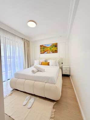 Una habitación de hotel con una cama grande, una mesita de noche, un cuadro y vistas a través de la ventana.