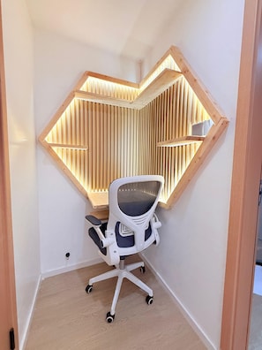 A corner office with a white desk chair, a slanted ceiling with wooden beams, and a wall-mounted shelf. - Stylish 2BR Retreat in the Heart of Westlands (Nairobi)