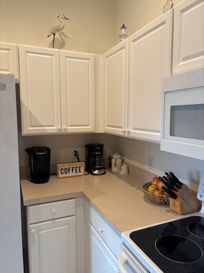A kitchen with white cabinets, a coffee maker, a microwave, and a fruit basket. - Escape Winter in Fort Myers Furnished 2BR/2BA Colonial Country Club (Fort Myers)