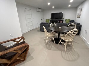 A modern living room with a dining table, chairs, a sofa, and a flat-screen TV. - A quiet Oak Bluffs retreat steps from Circuit Avenue and Inkwell Beach. (Oak Bluffs)