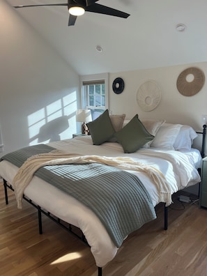 A bedroom with a bed, a ceiling fan, a window, and wall decor. - A quiet Oak Bluffs retreat steps from Circuit Avenue and Inkwell Beach. (Oak Bluffs)