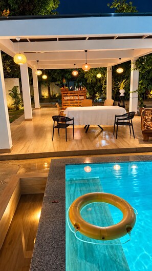 An outdoor pool area with a wooden deck, lounge chairs, and a bar area with a sign reading 'QUINTA DA GABI'. - Quinta da Gabi (Viana)
