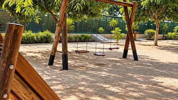 Un parque infantil con columpios y arena.