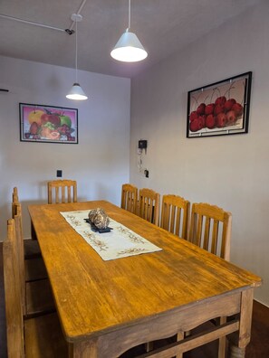 A dining area with a wooden table, six chairs, two pendant lights, and two framed fruit paintings on the walls. - GRANDPARENTS' HOME: THE BEST PLACE FOR A FAMILY GETAWAY (Ocotlán de Morelos)