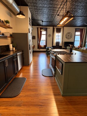 A kitchen with a central island, wooden flooring, and a decorative ceiling.