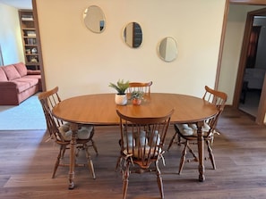 A dining table with four chairs, a potted plant, and three wall mirrors. - The Capsule: 60s Charm + Private Movie Theater (Sioux Falls)