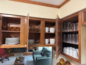 Une cuisine avec des placards ouverts où sont exposés différents plats et articles de verrerie.