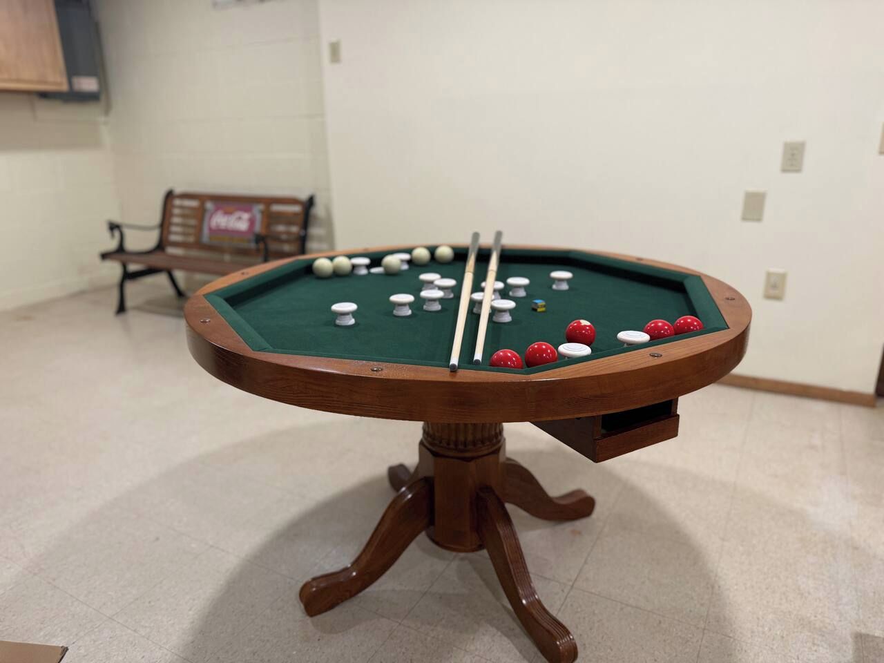 Een pooltafel met ballen en stokken, een bank en een muur met een bord.