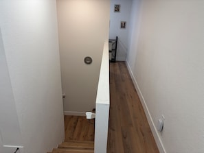 A narrow stairway with wooden flooring, white walls, and a white door at the top. - Cozy basement 1B1B apt. in Barnum neighborhood, 10mins from city & mtns (Denver)