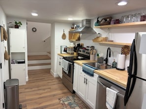 A modern kitchen with white cabinetry, stainless steel appliances, and wooden flooring. - Cozy basement 1B1B apt. in Barnum neighborhood, 10mins from city & mtns (Denver)