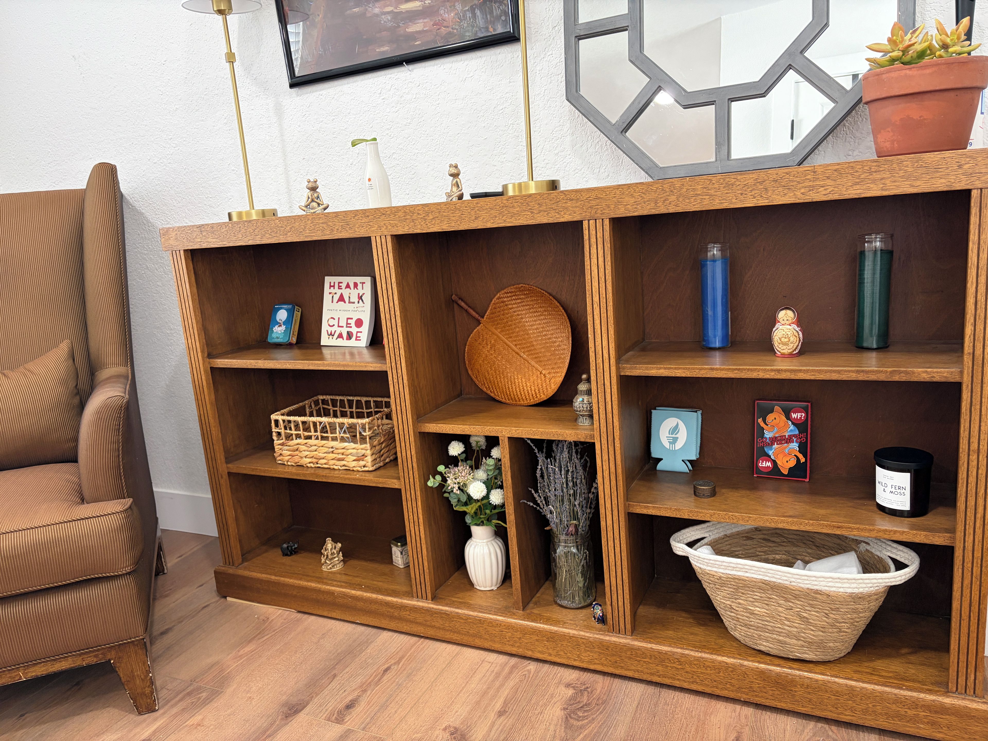 A wooden console with shelves, a woven basket, and decorative items.