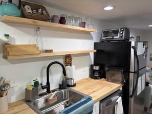 Eine moderne Küche mit Spüle aus Edelstahl, einer Kaffeemaschine und einem schwarzen Toaster auf der Arbeitsplatte.