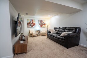 A living room with a leather sofa, two armchairs, a coffee table, and artwork on the walls. - 4BR Modern Farmhouse, Golf Views  Sleeps 10 (Belton)