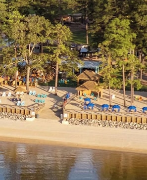 A beachside resort with a wooden pier, lounge chairs, and thatched-roof structures. - Tee Time is a Cozy 2 Bed 3 Bath Villa In Rayburn Country Resort (Brookeland)