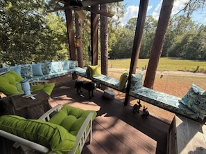 Eine Terrasss mit einer Couch und Stühlen, umgeben von Bäumen.