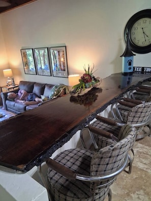 A long dining table with six chairs, a clock, and framed artwork on the wall. - Tee Time is a Cozy 2 Bed 3 Bath Villa In Rayburn Country Resort (Brookeland)