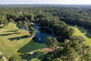 A golf course with a pond, surrounded by dense forest. - Tee Time is a Cozy 2 Bed 3 Bath Villa In Rayburn Country Resort (Brookeland)