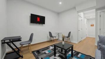 Una sala de estar moderna con un televisor de pantalla plana, una mesa de centro y dos sillones.