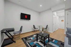 Una sala de estar moderna con un televisor de pantalla plana, una mesa de centro y dos sillones.