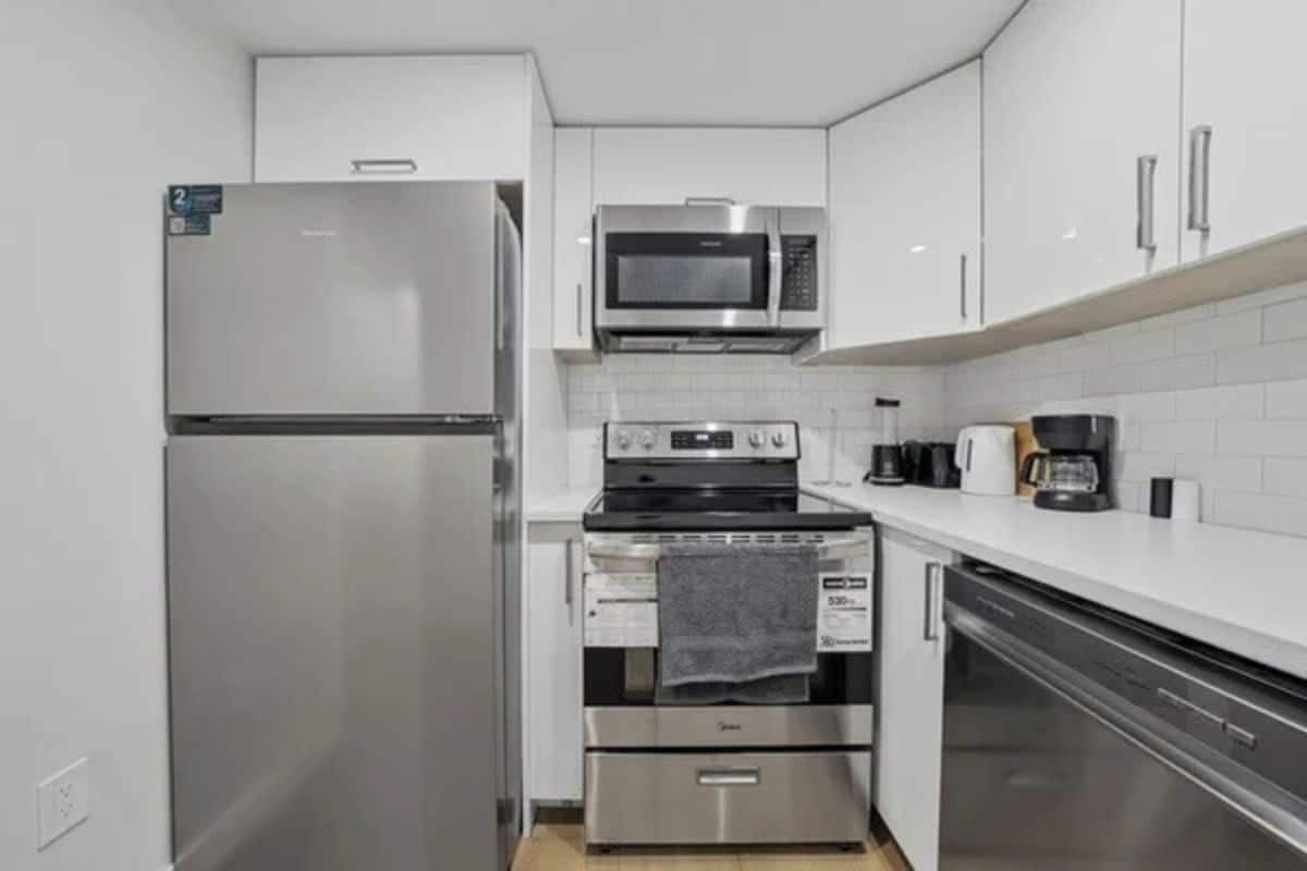 Una cocina compacta equipada con refrigerador, microondas, estufa, horno y lavavajillas.
