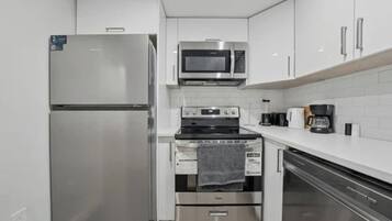 Una cocina compacta equipada con refrigerador, microondas, estufa, horno y lavavajillas.