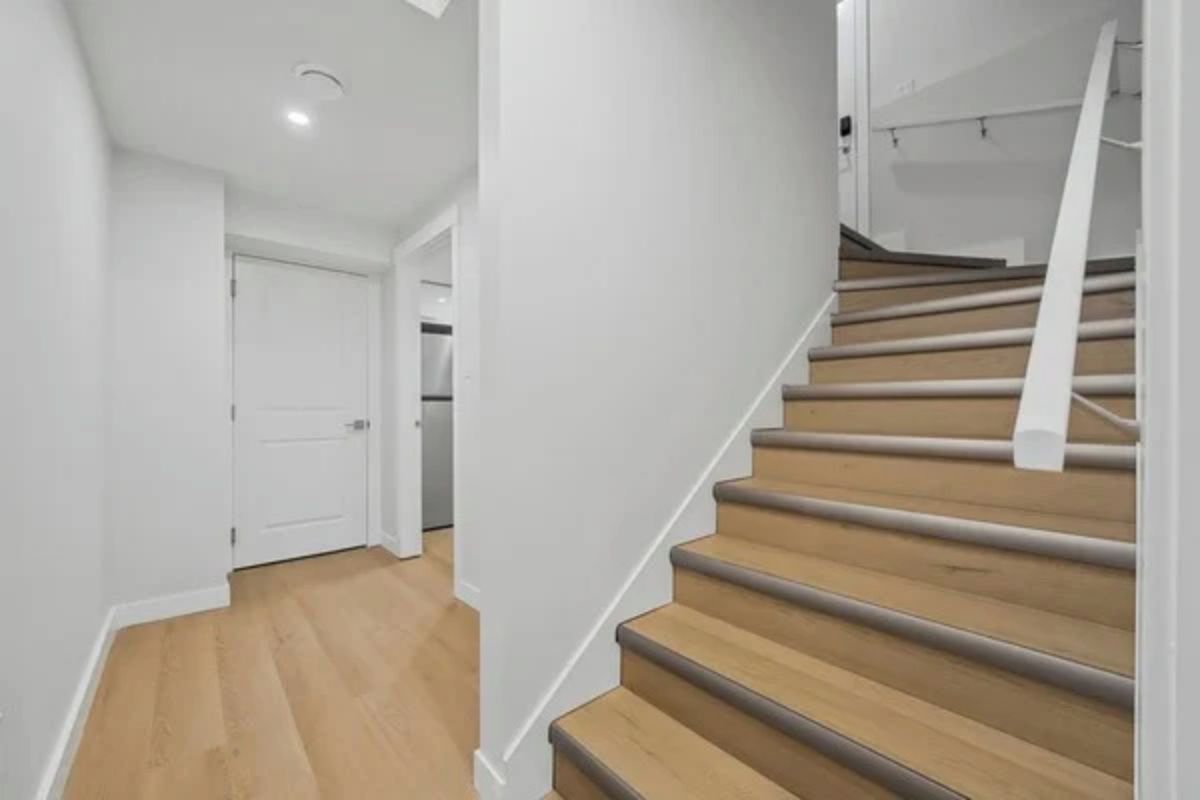 A staircase with wooden steps and white handrails, leading to an upper floor.