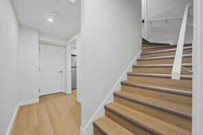 Una escalera con escalones de madera y barandillas blancas, que conduce a un piso superior.