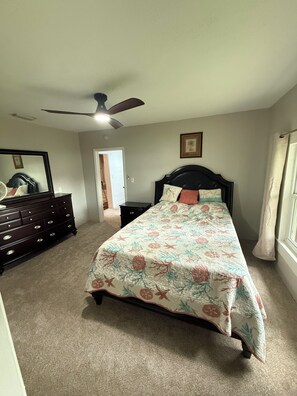 A bedroom with a bed, dresser, ceiling fan, and a door leading to another room. - Lake Panasoffkee retreat 2brm/2bath with boat parking (Lake Panasoffkee)