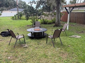 An outdoor patio with a round table and four chairs, surrounded by grass and trees. - Lake Panasoffkee retreat 2brm/2bath with boat parking (Lake Panasoffkee)
