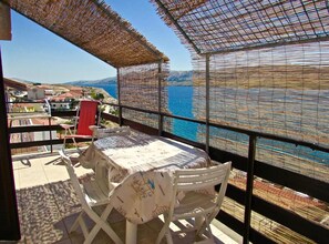 A balcony with a table and chairs, overlooking a body of water and a coastal town. - Cozy Apartments Drazica 4 (Novalja)
