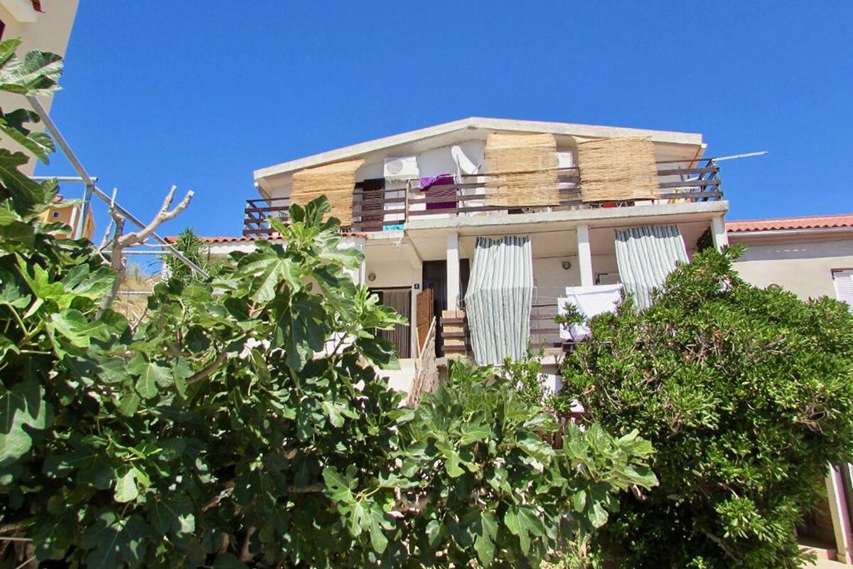 A two-story house with a balcony, a staircase leading to the upper floor, and a garden in the foreground.