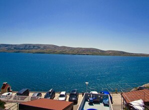 A coastal view with a clear sky, a body of water, and a hilly landscape in the distance. - Cozy Apartments Drazica 4 (Novalja)