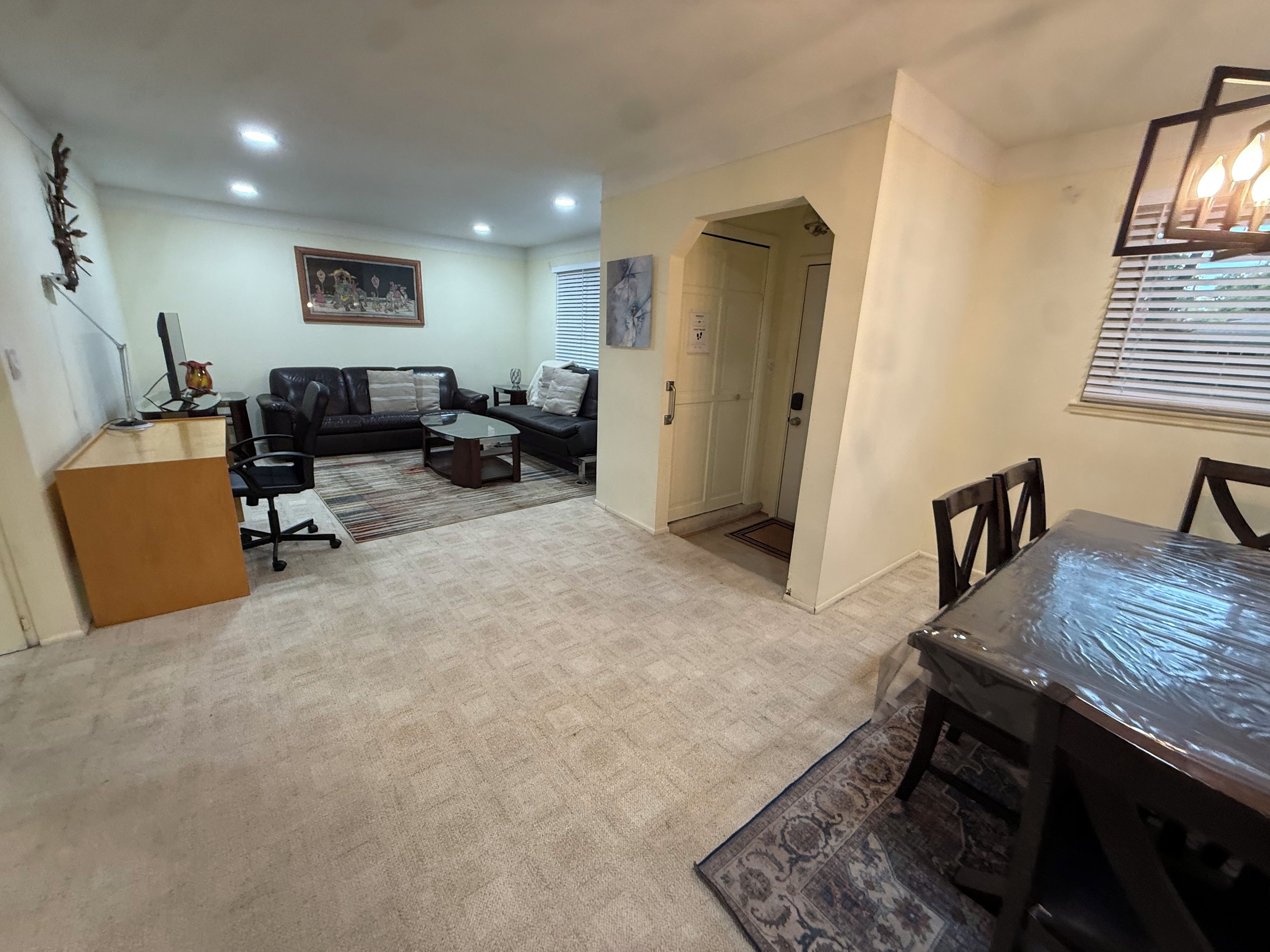 Una sala de estar con sofá, mesa de centro y comedor con mesa y sillas.