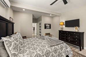 A bedroom with a bed, dresser, TV, and artwork. - Historic Borden House: Hot Tub Sauna Pet Friendly (Galveston)