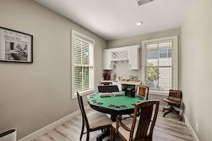 A dining area with a green table, wooden chairs, and a white cabinet above the counter. - Historic Borden House: Hot Tub Sauna Pet Friendly (Galveston)