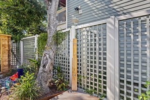 Um deck de madeira leva a uma casa com cerca branca, uma árvore e um aviso com instruções para limpeza de animais de estimação.