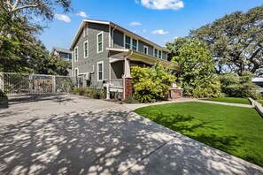 Ein zweistöckiges Haus mit Veranda, umzäunter Garten und gepflegtem Rasen.