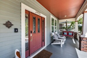 A house with a red door, a porch with white rocking chairs, and a brick fireplace. - Historic Borden House: Hot Tub Sauna Pet Friendly (Galveston)