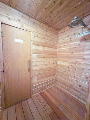 A wooden cabin with a door, a shower area, and a ceiling-mounted light fixture. - 4BR Big Sky Condo with Private Hot Tub & Sauna (Big Sky)