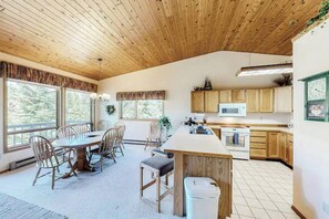 A spacious kitchen with wooden cabinets, a central island, and a dining area with chairs. - 4BR Big Sky Condo with Private Hot Tub & Sauna (Big Sky)