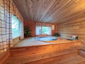 A wooden cabin with a hot tub, wooden floors, and large windows. - 4BR Big Sky Condo with Private Hot Tub & Sauna (Big Sky)