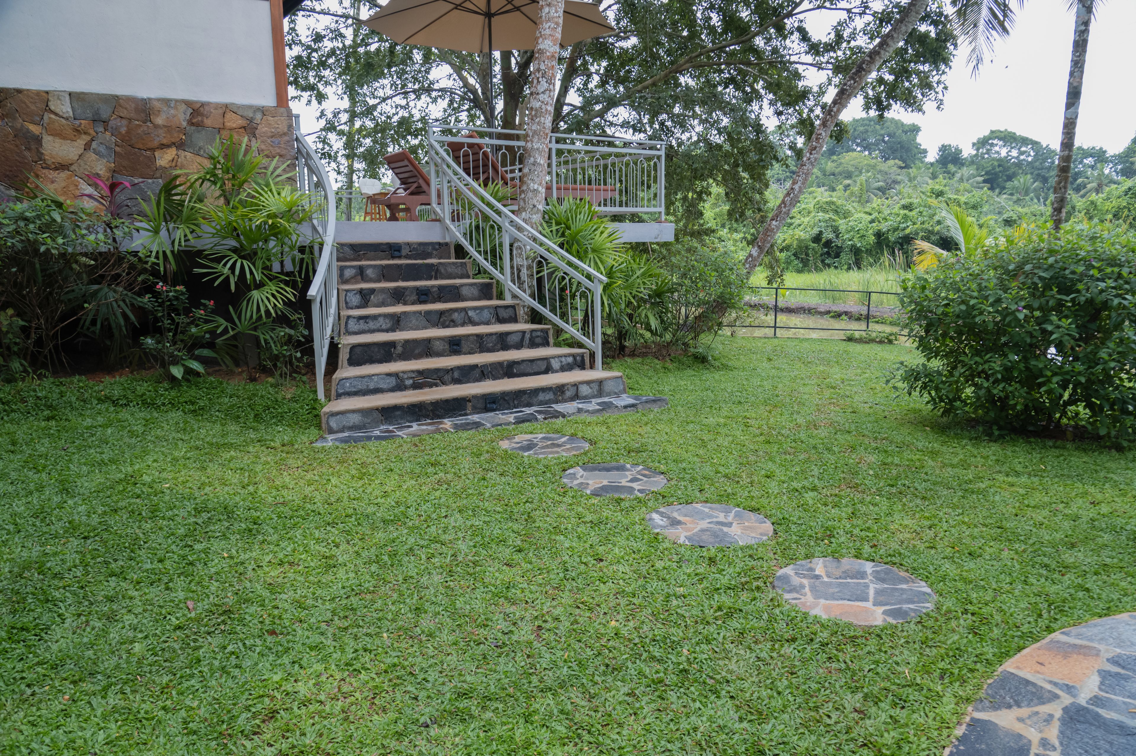 Una escalera de piedra que lleva a un espacio al aire libre cubierto con vistas a un jardín exuberante.