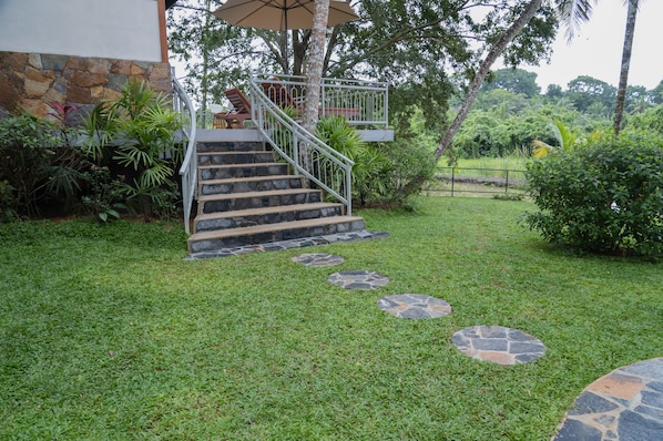 Una escalera de piedra que lleva a un espacio al aire libre cubierto con vistas a un jardín exuberante.